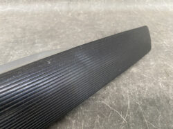 Close-up of a black ribbed grip on a long cylindrical object resting on a gray surface.