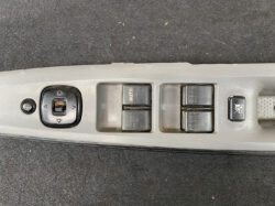 Car interior door panel with power window and mirror controls: four window switches, a lock button, and a circular mirror-adjustment pad.