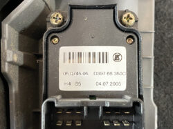 Close-up of a black electronic module with a barcode label and four screws, featuring a multi-pin connector at the bottom.