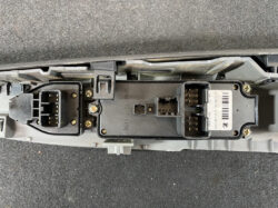 Close-up of a car’s behind-dash electrical module with several multi-pin connectors and visible screws.