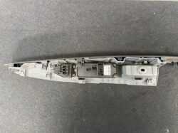 Long gray automotive control module with two connector housings and a barcode sticker on a dark surface.
