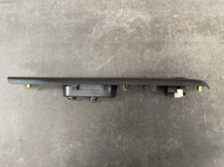 Long black car radio faceplate with connectors at one end, laid on a scratched surface.