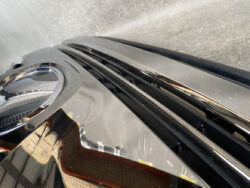 Close-up of a shiny black car panel with chrome trim and light reflections.