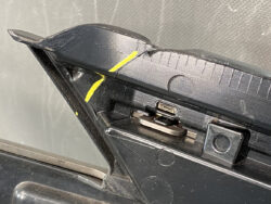 Close-up of a cracked black plastic hinge with a USB port exposed and yellow tape marks on the damaged edge.