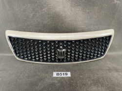 Front car grille with a chrome frame, black honeycomb insert, and a central emblem.