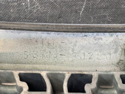 Close-up of stamped serial numbers on a dusty metal surface (likely a car engine part).