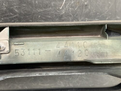 Close-up of a metal vehicle VIN plate with embossed numbers (53111-44110) on the car frame.