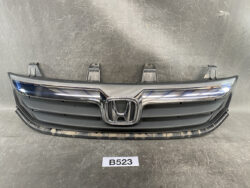 Front view of a Honda car grille with chrome emblem and horizontal slats on a dark bumper backdrop