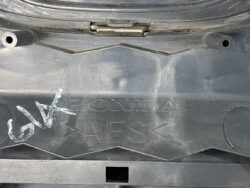 Close-up of a black plastic car part with embossed 'HONDA' and 'AES' lettering and a small rectangular opening below.”],