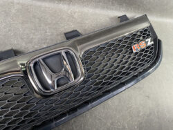 Front grille of a Honda car featuring the chrome emblem and a red RSZ badge on a honeycomb mesh background