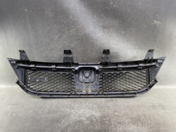 Black plastic car grille with honeycomb mesh and mounting points for a front bumper