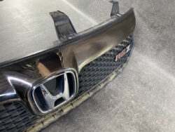Front grille of a black car with a Honda emblem and a red 'RS' badge visible on the right side of the grille.