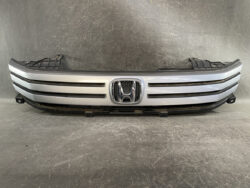 Front grille of a silver Honda car with the emblem in the center, viewed from the front.