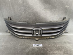 Front grille assembly for a Honda vehicle with the silver Honda emblem in the center; black horizontal slats and mounting brackets visible.