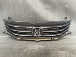 Front grille assembly from a Honda vehicle with the chrome H emblem in the center, black horizontal slats, and mounting tabs visible on the sides.