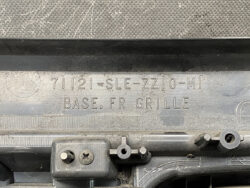 Close-up of a dusty car grille base with embossed text reading 'BASE, FR GRILLE'.