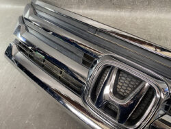 Close-up of a shiny chrome Honda front grille with the emblem at the center.
