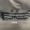 Chrome Honda front grille with classic 'H' emblem, resting on a workshop surface. HONDA FIT SHUTTLE JAZZ HYBRID GP2 Genuine Radiator Grille 71121-TF9-003 » JDM-PARTS NZ