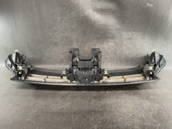 Plastic bumper support assembly with mounting brackets and clips for a vehicle, laid on a dark surface