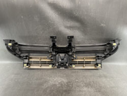 Front bumper fascia with mounting brackets and central grille area, lying on a workshop table.
