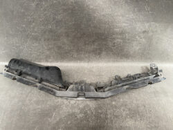 Black plastic car bumper cover piece with multiple mounting tabs laid on a metal surface. (Informative automotive part)