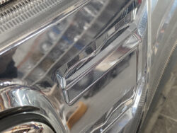 Close-up of a car's chrome bumper with a rectangular recessed area and reflective finish.