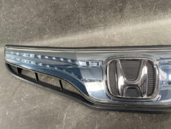 Close-up of a Honda front grille with a chrome surround and LED daytime running lights along the left edge.