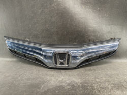 Front grille of a Honda car with chrome surround and emblem in the center