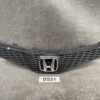 Black Honda front grille with honeycomb mesh and chrome emblem, resting on a workshop surface; label 'B531' beneath. HONDA FIT JAZZ GE6 GE7 Genuine Radiator Grille 71121-TF0-00 » JDM-PARTS NZ