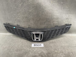 Black Honda front grille with honeycomb mesh and chrome emblem, resting on a workshop surface; label 'B531' beneath.