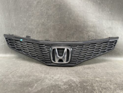 Front grille of a Honda car with the chrome emblem in the center on a dark background, ready for installation.