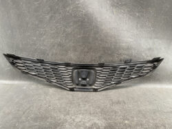 Front view of a black honeycomb car grille with a central emblem housing and mounting tabs on the edges (auto part).