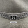 Front grille of a Honda car with a chrome honeycomb mesh and central Honda emblem