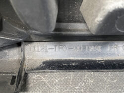 Close-up of a dusty automotive plastic surface with an embossed part number: 7L121-TE0-00 RASE FR.