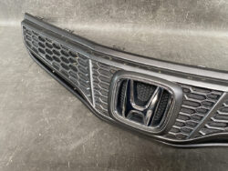 Front grille of a Honda vehicle with the chrome Honda emblem centered in a black honeycomb mesh