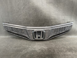 Front grille of a Honda car with a honeycomb mesh and the Honda emblem centered in the middle.