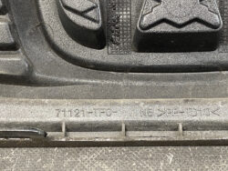 Close-up of a textured black plastic part with embossed serial numbers (e.g., '71121-TF0-'). The surface shows guide marks and a thin lip along the bottom edge.