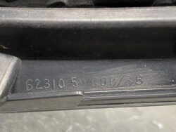 Close-up of a car door sill with embossed alphanumeric code (e.g., 62310 5WG0B/3B) for part identification.