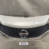 Front grille of a Nissan car with chrome emblem and black honeycomb pattern, hood above on a neutral surface, label B534 nearby. NISSAN NOTE E12 NE12 Genuine Radiator Grille 62310-3VA0A / 62312-3VA0A » JDM-PARTS NZ