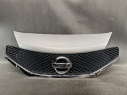 Front grille of a Nissan car with a diamond mesh pattern and a centered chrome badge.