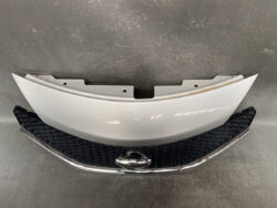 Front bumper cover and Nissan grille with chrome trim and emblem, likely from the car's front end.