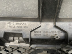 Close-up of black Nissan grille assembly plastic with molded part numbers 62310 and 62312.