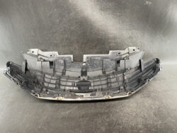 Curved black plastic car bumper cover with mounting clips and inner ribs.”,
