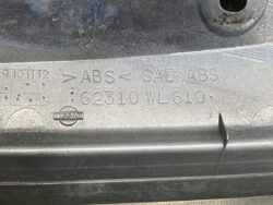 Close-up of a metal car part with ABS engraving, SAE ABS, part number 62310 WL 610, and a Nissan badge.