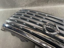 Close-up of a shiny chrome Nissan grille with the Nissan emblem in the center.