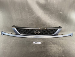 Front view of a blue Nissan car grille with a black honeycomb insert and emblem in the center, mounted on a matching bumper piece.