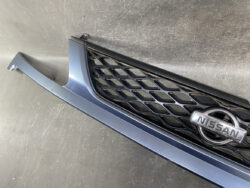 Blue front bumper and black honeycomb grille with Nissan badge visible on a car front end