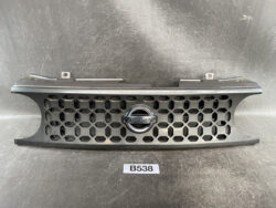 Nissan front grille with hexagonal honeycomb pattern and chrome Nissan emblem in the center