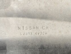 Close-up of a dusty metal surface showing a Nissan CK stamp and the part number 62313 4V70A, likely an identification mark on a vehicle part.