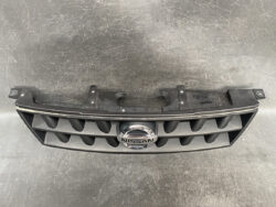 Front grille module from a Nissan car with the chrome Nissan badge in the center and mounting tabs visible behind it